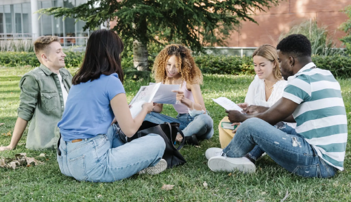 studenti tre ragazze e due ragazzi sono seduti su un prato in cerchio, parlano e leggono dei fogli che hanno in mano