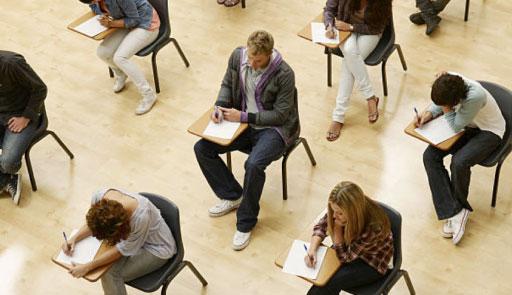 ragazzi e ragazze sedute ai banchi che scrivono durante un test ragazzi e ragazze sedute ai banchi che scrivono durante un test