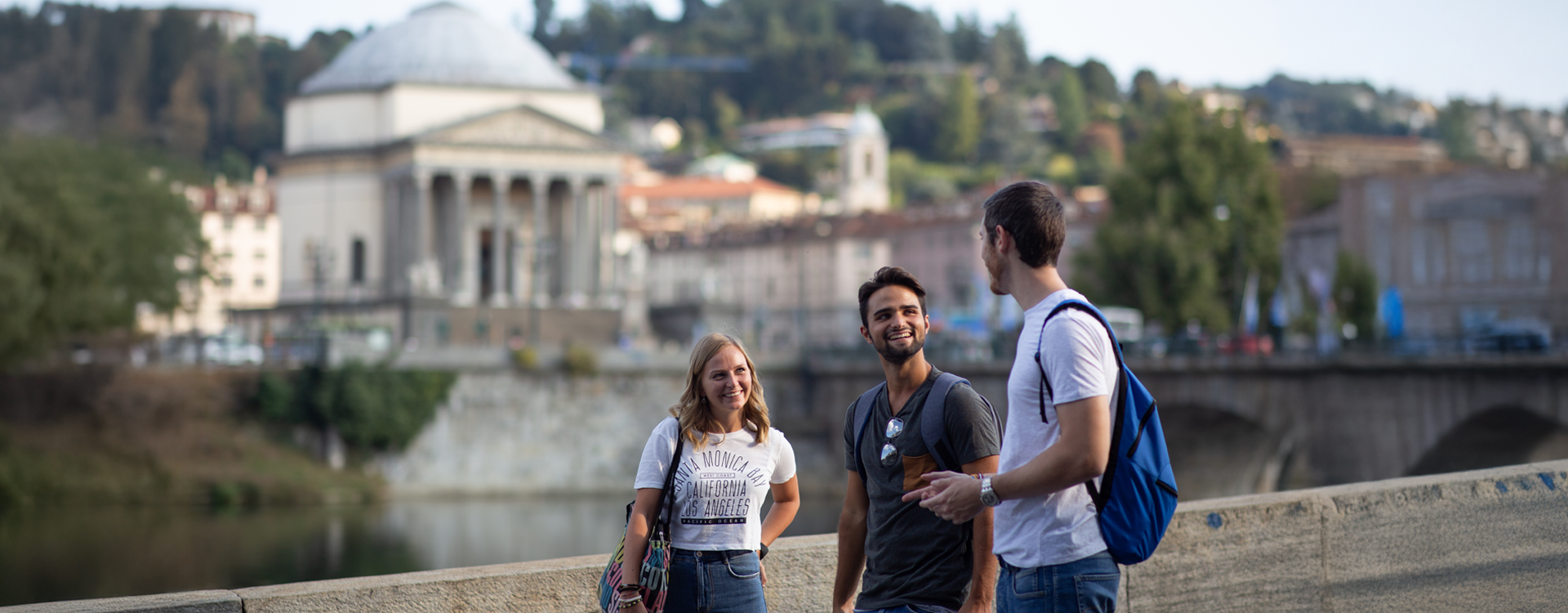 3 studenti sorridenti parlano con sullo sfondo la Gran Madre