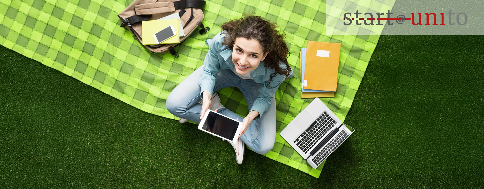 Studentessa con tablet, computer e libri che studia all'aperto