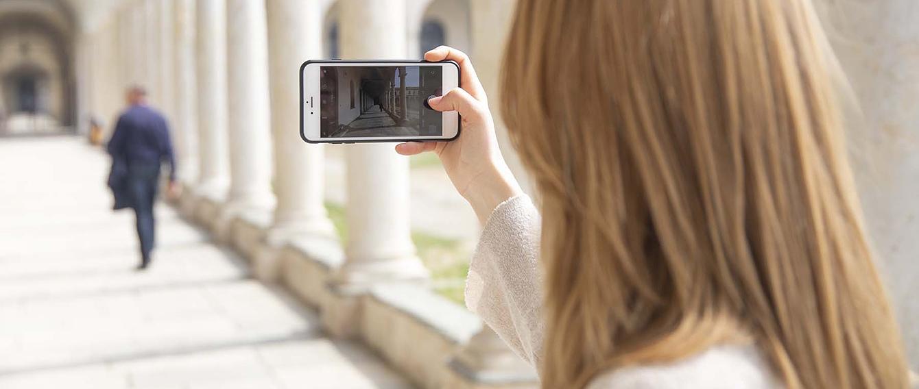 Giovane donna inquadra con lo smartphone il corridoio della sedi di Savigliano