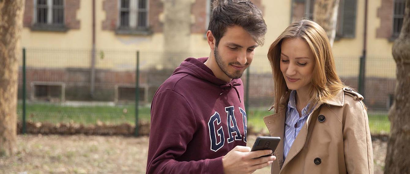 Un ragazzo e una ragazza in un parco guardano il cellulare