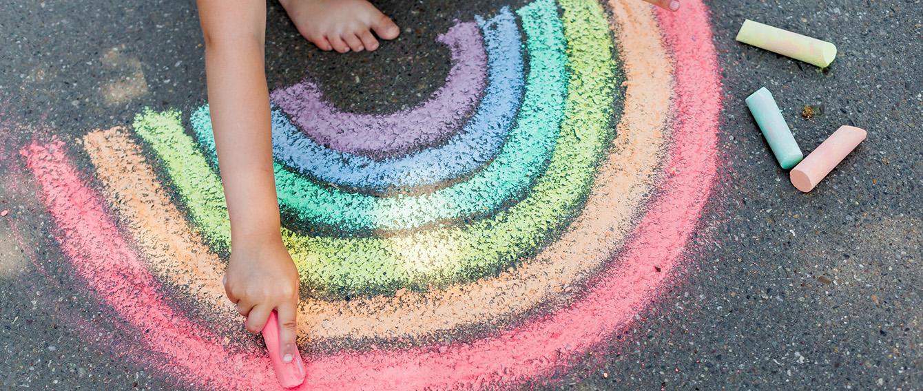 Getty images/tgordievskaya Mano di bambino che con un gessetto disegna un arcobaleno per terra