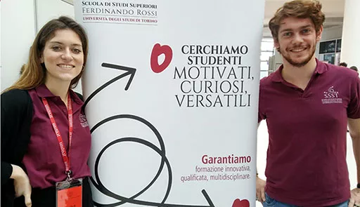 Scuola di Studi Superiori Ferdinando Rossi Un ragazzo e una ragazza sorridono di fianco al totem della Scuola Ferdinando rossi