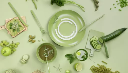 tavolo visto dall'alto con frutta, verdure, piatti e posate verdi