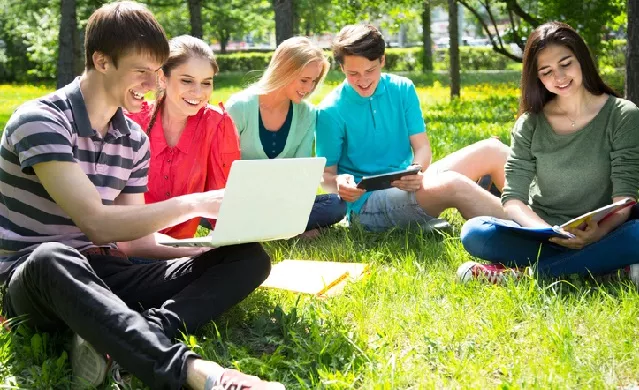 studenti con pc portatile, seduti su un prato
