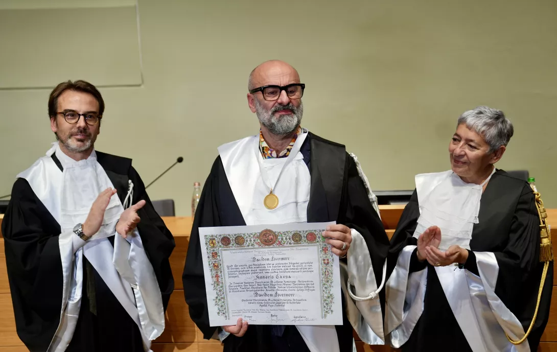 Due uomini sulla sinistra e una donna sulla destra che indossano la toga. L'uomo al centro ha in mano una pergamena