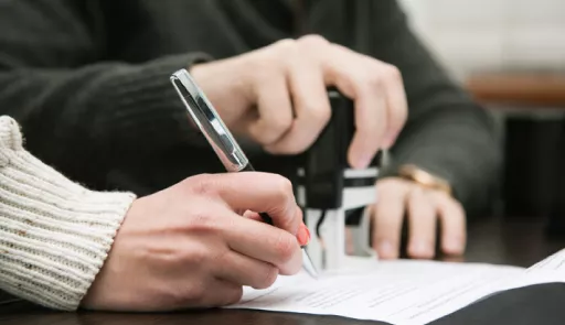 una mano impugna una penna per compilare un modulo